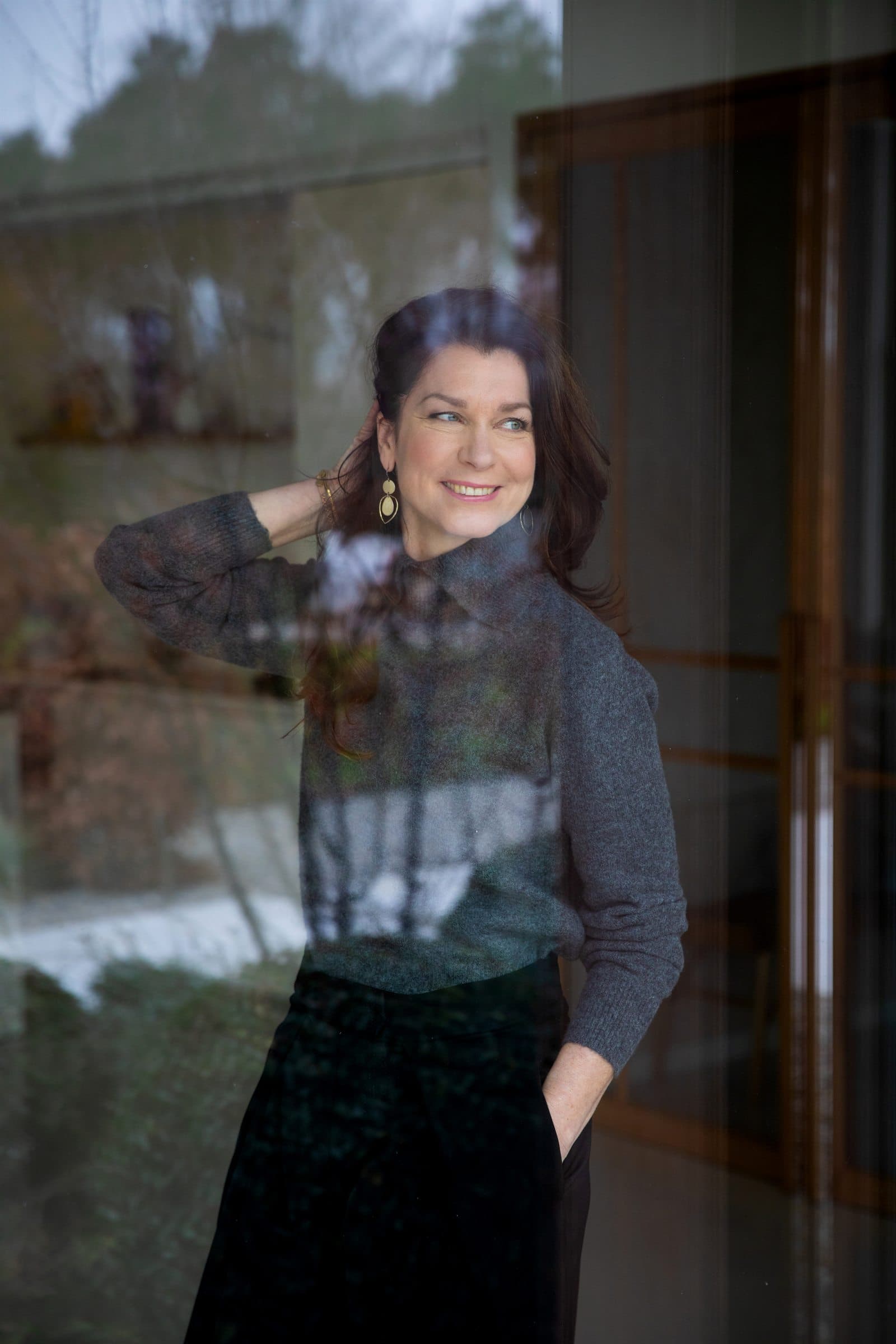 Mariska de Kleijne achter glas, met de omgeving weerspiegeld over haar portret